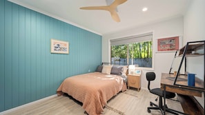 A bedroom with a bed, a desk, and a window with a view of greenery. - Salt & Sand Beach House - 6 bedrooms (Ocean Shores)