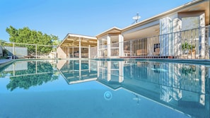 A clear swimming pool with a glass bottom, surrounded by a covered patio area with outdoor furniture. - Salt & Sand Beach House - 6 bedrooms (Ocean Shores)