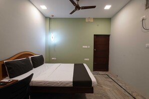 A bedroom with a bed, a desk, a chair, a ceiling fan, and a door. - Villa Tian by Palette Homes (Chennai)