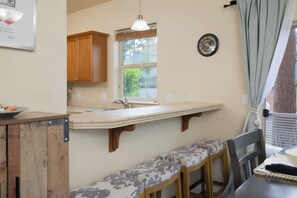 A kitchen with wooden cabinets, a built-in bench, a window, and a wall clock. - Bend Hideaway • Near Mt. Bachelor + Breweries | Hollygrape Pedal & Pine Hideaway (Bend)