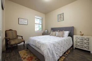 A bedroom with a bed, a chair, a nightstand, and a window. - Bend Hideaway • Near Mt. Bachelor + Breweries | Hollygrape Pedal & Pine Hideaway (Bend)