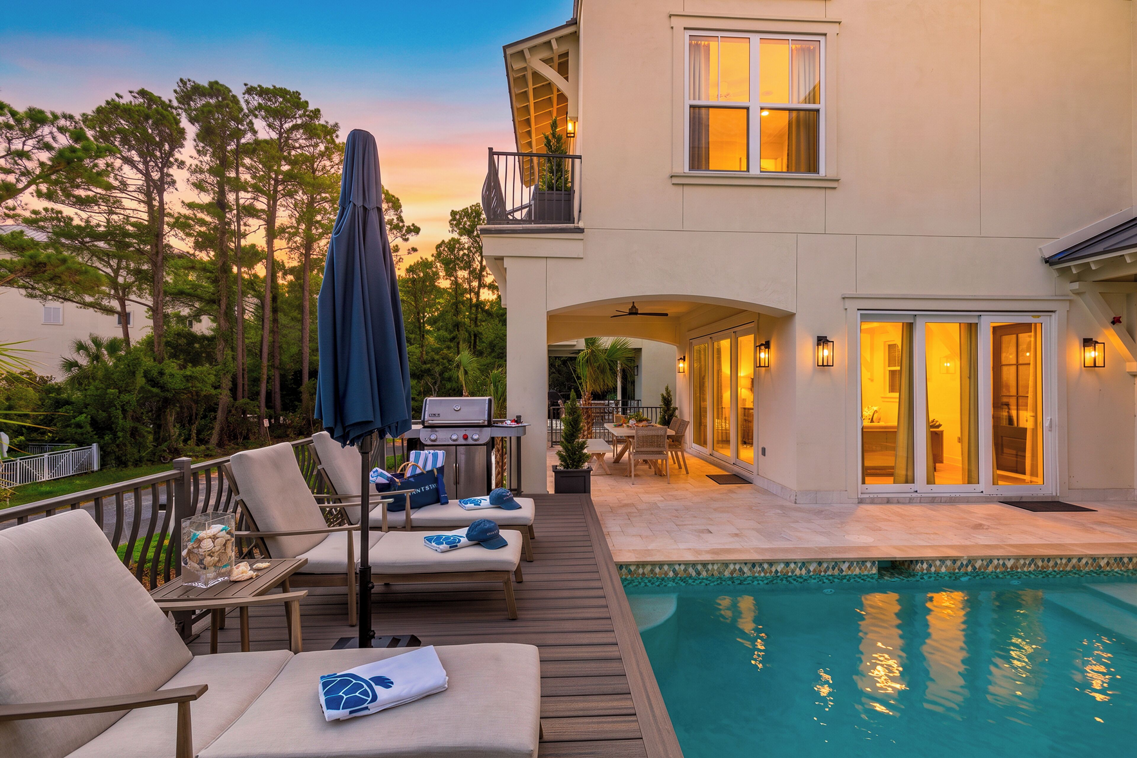 A poolside area with lounge chairs, a grill, and a view of the pool.