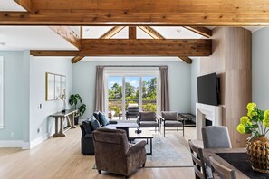 A spacious living room with a high ceiling, a fireplace, and a large window offering a view of the outdoors. - Private Infinity Pool + Elevator + Pool Table | Steps to Sand | Boardwalk & Blue (Hilton Head Island)