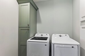 A laundry room with two front-loading washing machines and a cabinet. - Private Infinity Pool + Elevator + Pool Table | Steps to Sand | Boardwalk & Blue (Hilton Head Island)