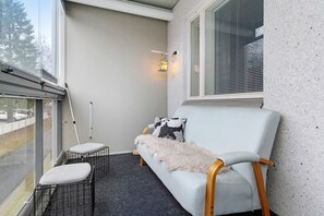 A balcony with a light grey sofa, a fluffy throw blanket, a metal chair, and a small table. - Nordic Heart Apartment, Sauna By Lapland Host (Rovaniemi)