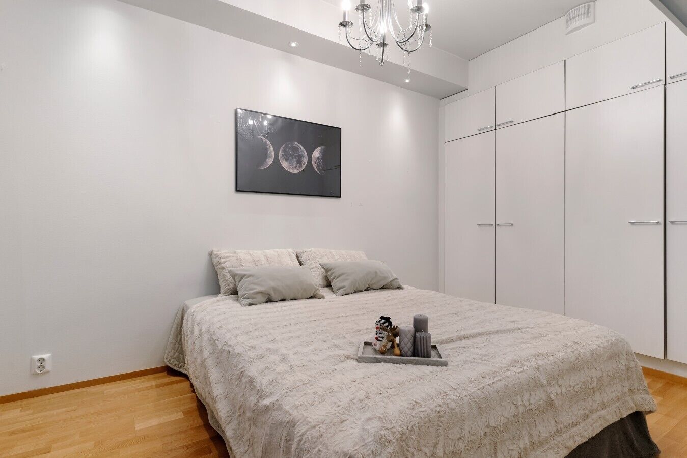 Ein Schlafzimmer mit einem Bett, einer Kandelaber, einem Kleiderschrank und einem Wandbild.
