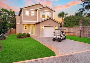 Ein zweistöckiges Haus mit Garage, Auffahrt und Golfwagen vor der Tür.