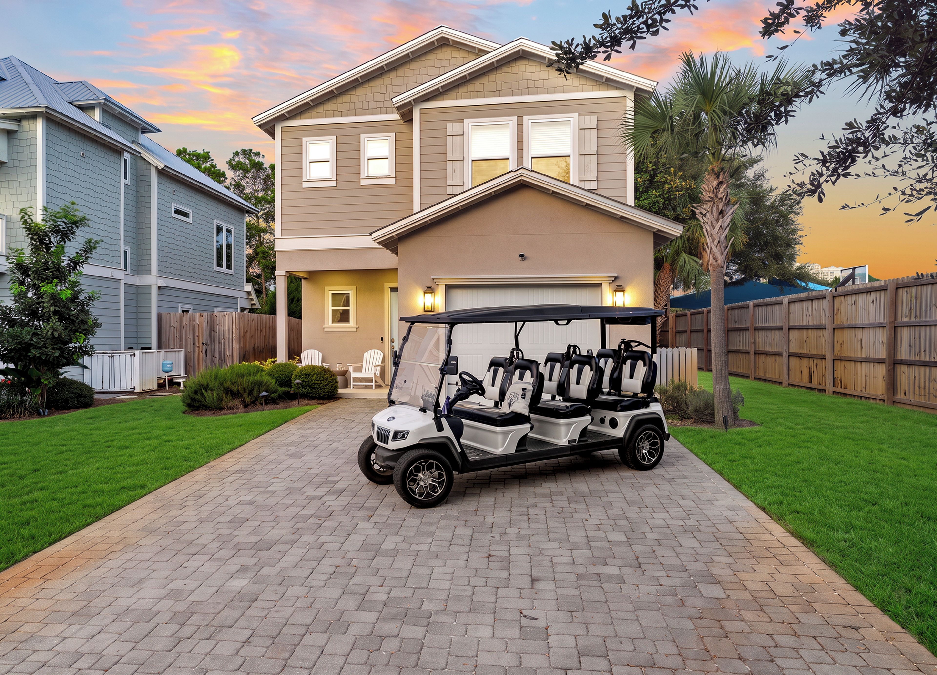 Une allée menant à une résidence, avec une voiturette de golf garée devant une maison à deux étages dotée d’un garage.