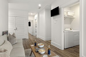 Ein modernes Wohnzimmer mit einer Couch, einem Couchtisch mit Snacks und Getränken sowie einem an der Wand befestigten Flachbildfernseher.