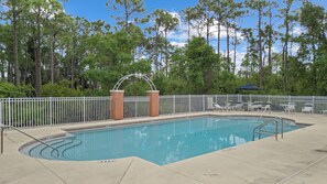 A swimming pool with a white fence, surrounded by trees and a clear sky. - Golf Cart + Game Room + Pool Access | Steps to the Sand | Sundrift (Miramar Beach)