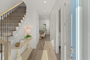 A staircase with wooden steps and metal balusters, leading to a landing with a lamp and a small plant. - Golf Cart + Game Room + Pool Access | Steps to the Sand | Sundrift (Miramar Beach)
