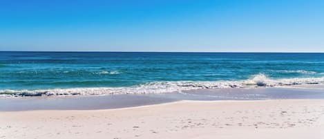 A beach with clear blue water and a sandy shore.