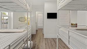 Quarto com beliches, TV de tela plana na parede e janela com vista para o exterior.