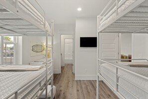 Una habitación con literas, un televisor de pantalla plana montado en la pared y una ventana con vistas al exterior.