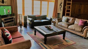 A living room with a television, two sofas, a coffee table, and a wooden ladder.