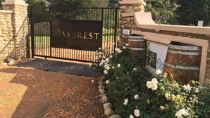 A gated entrance with a sign reading 'AKSREST' and stone pillars with spherical tops.