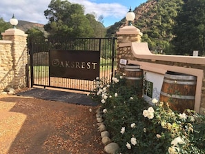 A gated entrance with a sign reading 'AKSREST' and stone pillars with spherical tops.
