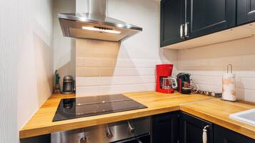 Een moderne keuken met een ingebouwde kookplaat, oven en een koffieapparaat.