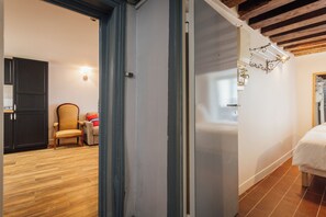 A room with a wooden floor, a bed, a chair, and a wardrobe.