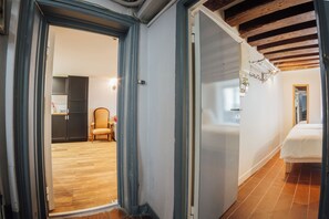 A room with a bed, a chair, and a kitchen area visible through an open door. - Fully equipped new 2BR 2BA one BR/BA individual entrance in Central Paris (Paris)