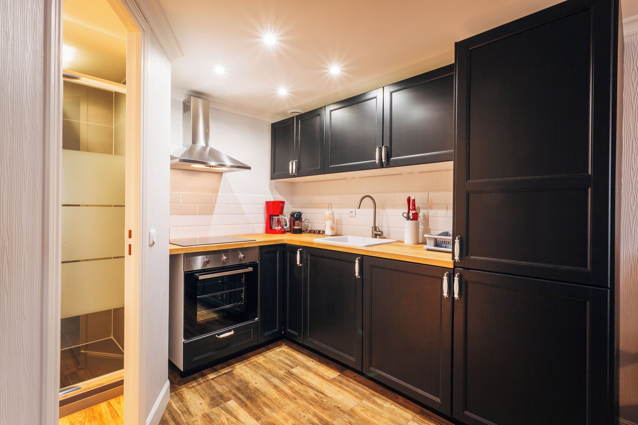 Une cuisine moderne avec des meubles de couleur sombre, un four en acier inoxydable et un plan de travail en bois.