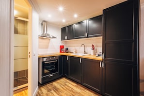 A modern kitchen with dark cabinets, a stainless steel oven, and a wooden countertop.
