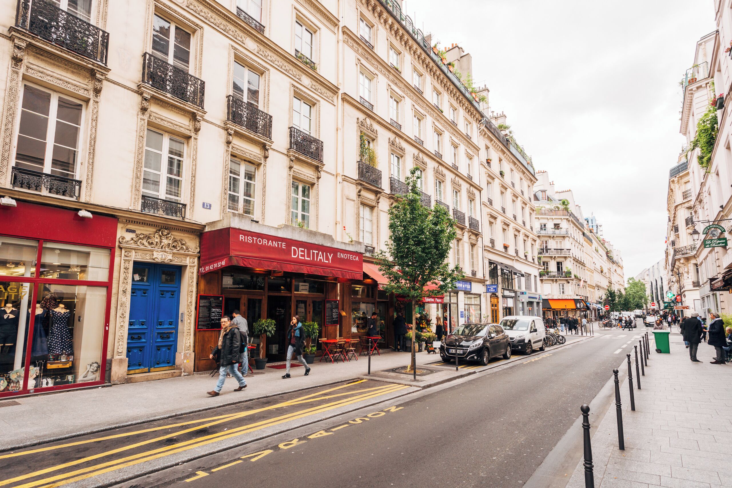 A street with buildings, a restaurant named 'Delitaly', and a blue door.