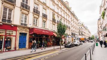 A street with buildings, a restaurant named 'Delitaly', and a blue door.