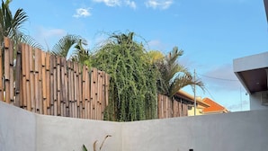 A swimming pool with a concrete edge, surrounded by a low wall with plants. - BUBU Villa Ubud  (Ubud)