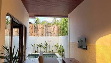 Un comedor interior con vistas a la piscina, muebles de madera y una lámpara colgante.