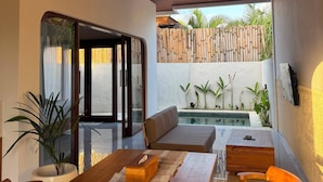 An outdoor dining area with a pool, wooden furniture, and a woven light fixture. - BUBU Villa Ubud  (Ubud)