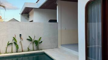 Un área de piscina moderna al aire libre con una piscina cristalina, una zona de estar cubierta y vistas al cielo.