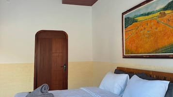Habitación de hotel con una cama, un cuadro, una puerta de madera y un techo con diseño decorativo.