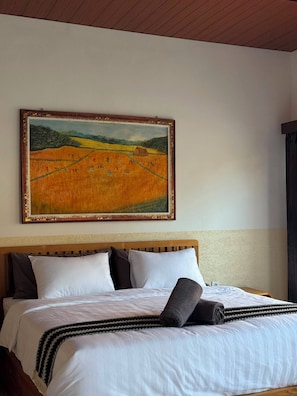 A hotel room with a large bed, a headboard, and a painting of a field on the wall. - BUBU Villa Ubud  (Ubud)