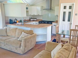 A compact living space with a kitchenette, a sofa, and a glass dining table. - 2 bedroom accommodation in Newquay (Newquay)