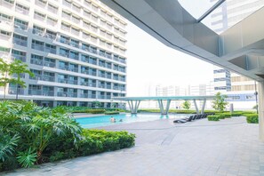 Edifici modern amb múltiples balcons, una piscina i una zona exterior coberta amb seients.