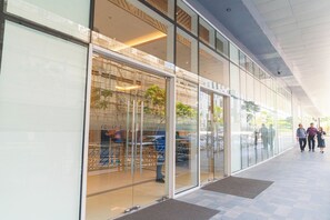 A modern building with large glass windows, a covered entrance, and a tiled floor. - Elegant Stay in Prime Location for Traveler Near BGC, Makati, Ortigas & MRT (Mandaluyong City)