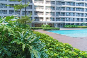 A modern hotel with a swimming pool surrounded by lush greenery. - Elegant Stay in Prime Location for Traveler Near BGC, Makati, Ortigas & MRT (Mandaluyong City)