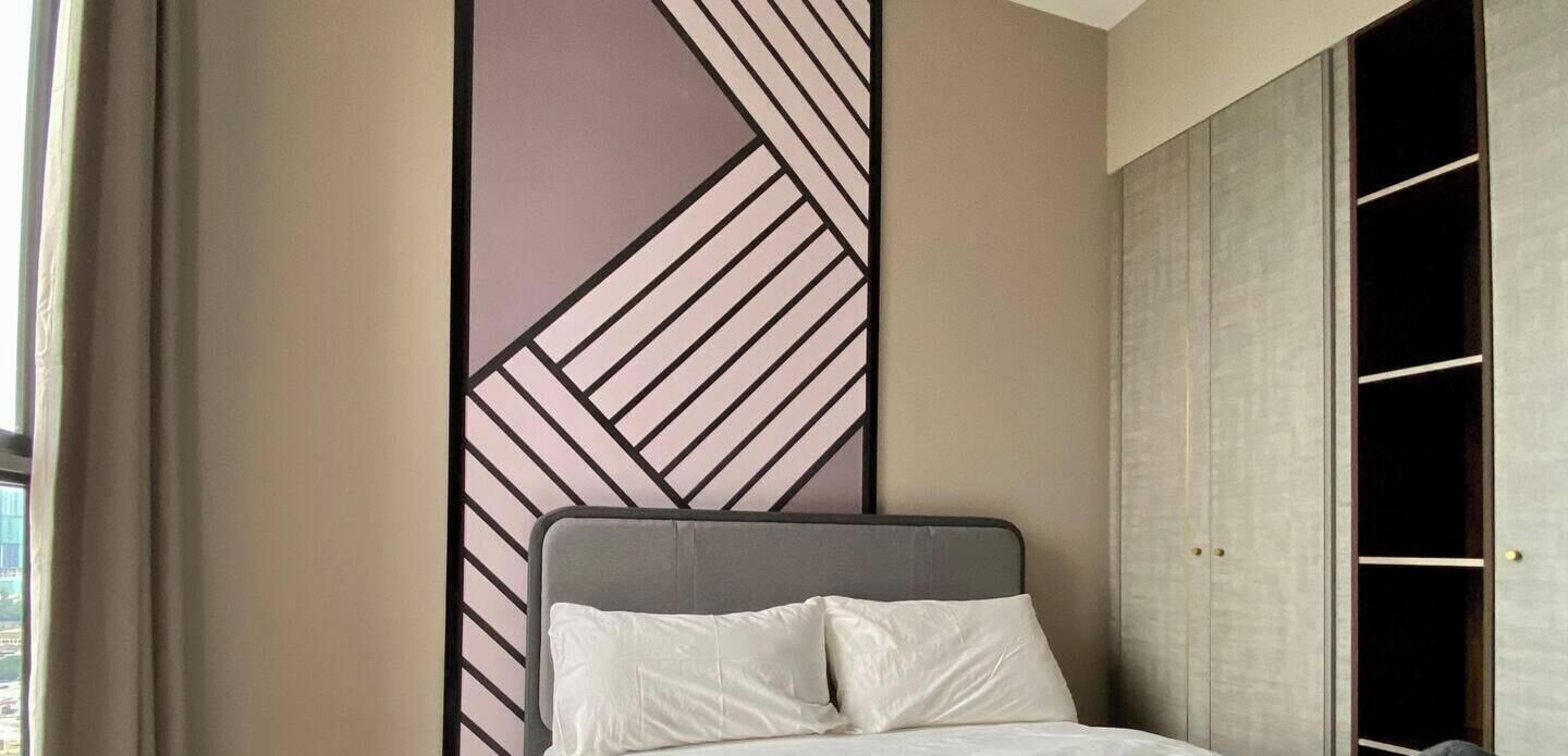 Un dormitorio con cama, armario y un panel decorativo en la pared.