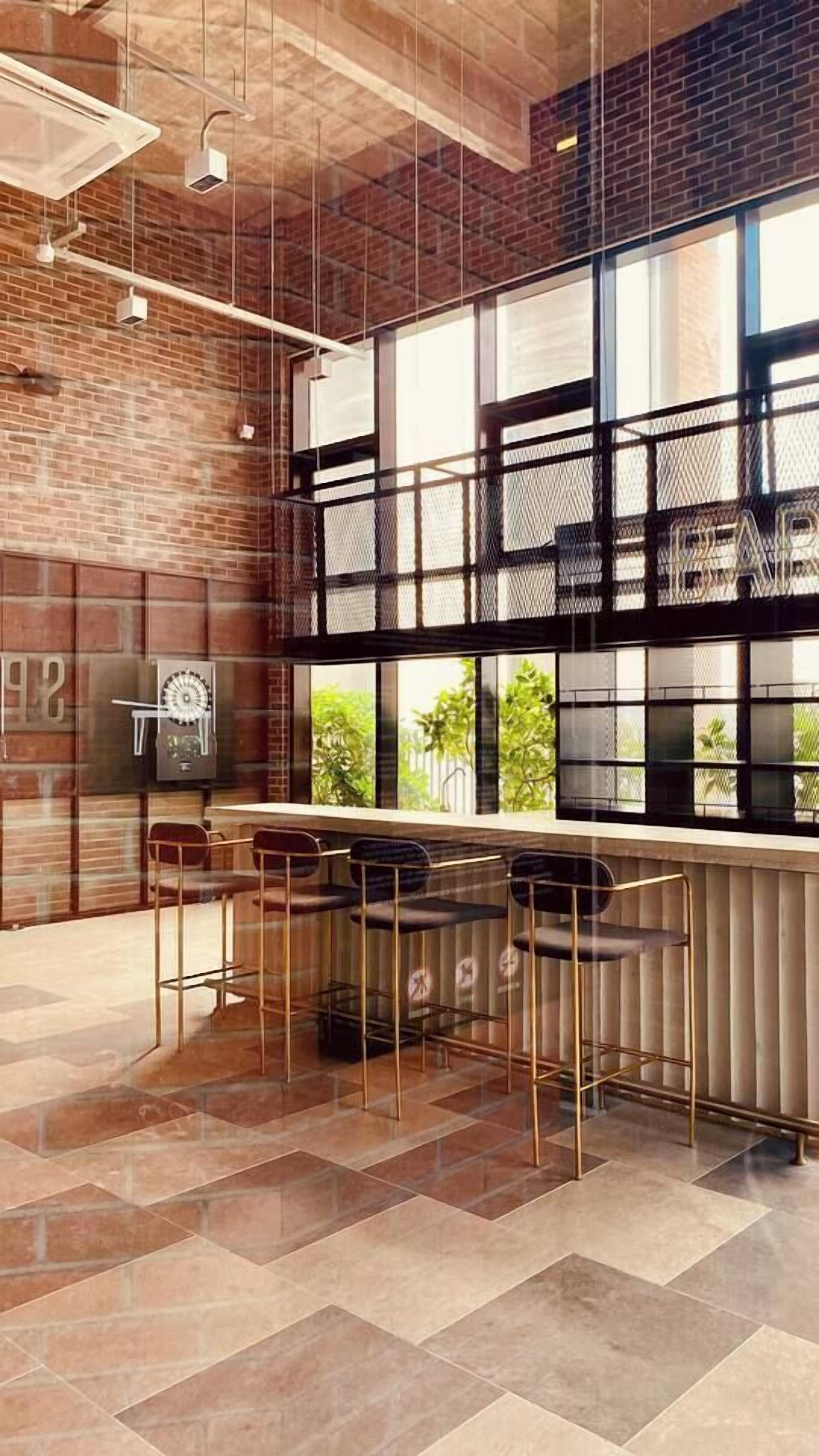 A modern bar area with a brick wall, large windows, and a tiled floor.