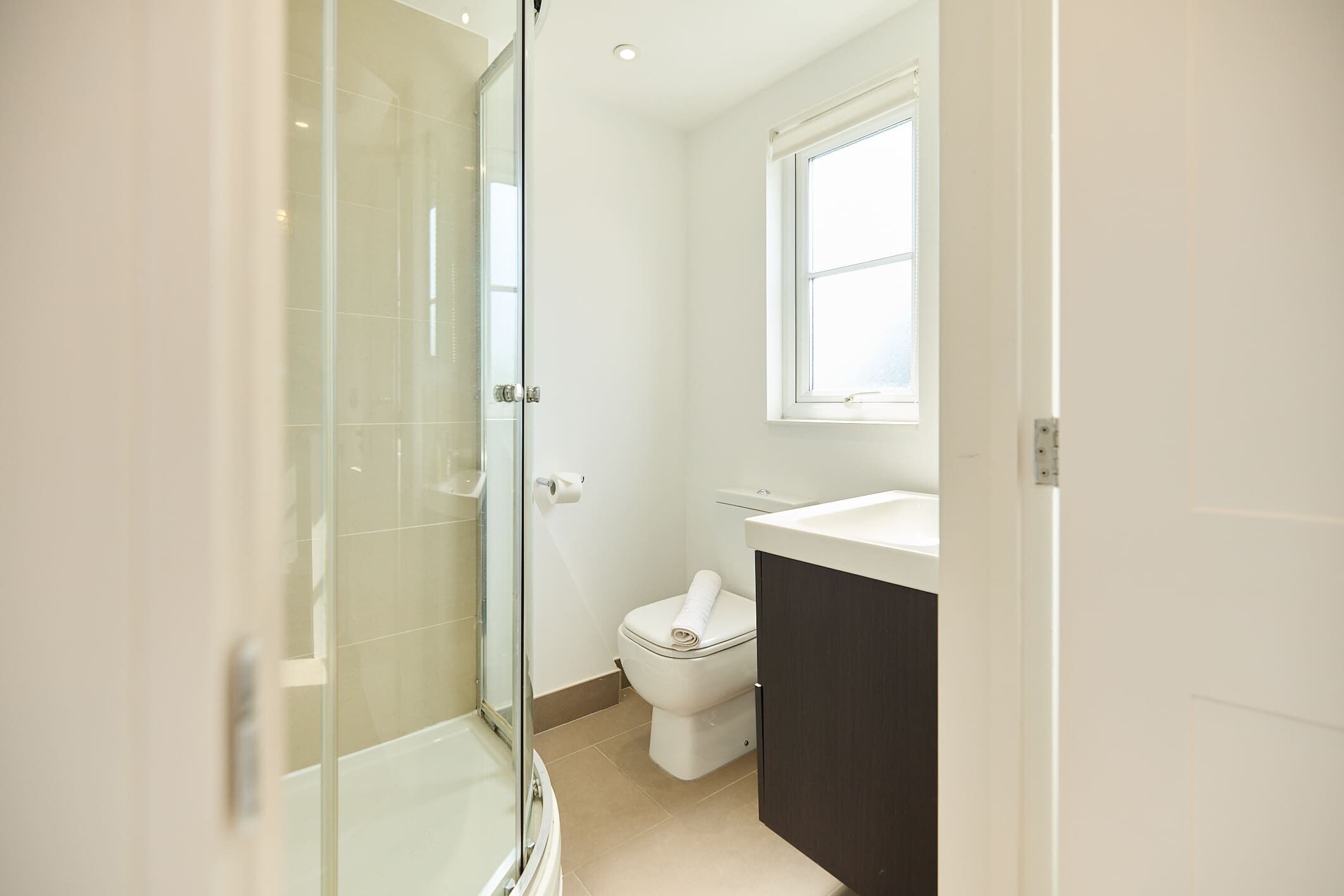 Ein Badezimmer mit Duschkabine aus Glas, Toilette und Waschbecken.