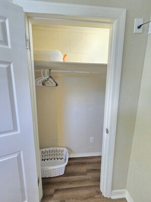 A narrow hallway with a white door on the left, a white laundry basket on the floor, and a white wall with a white baseboard. - 4BD 2BT 2 Parkings House Orlando Pine Hills Viet Town Disney Lego Airport (Orlando)