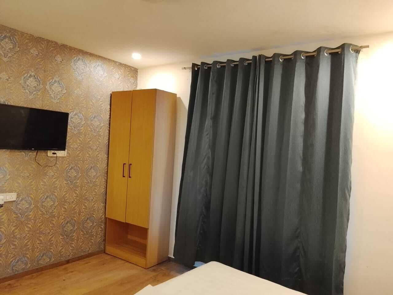 Habitación con armario, televisor de pantalla plana en la pared y cortina.