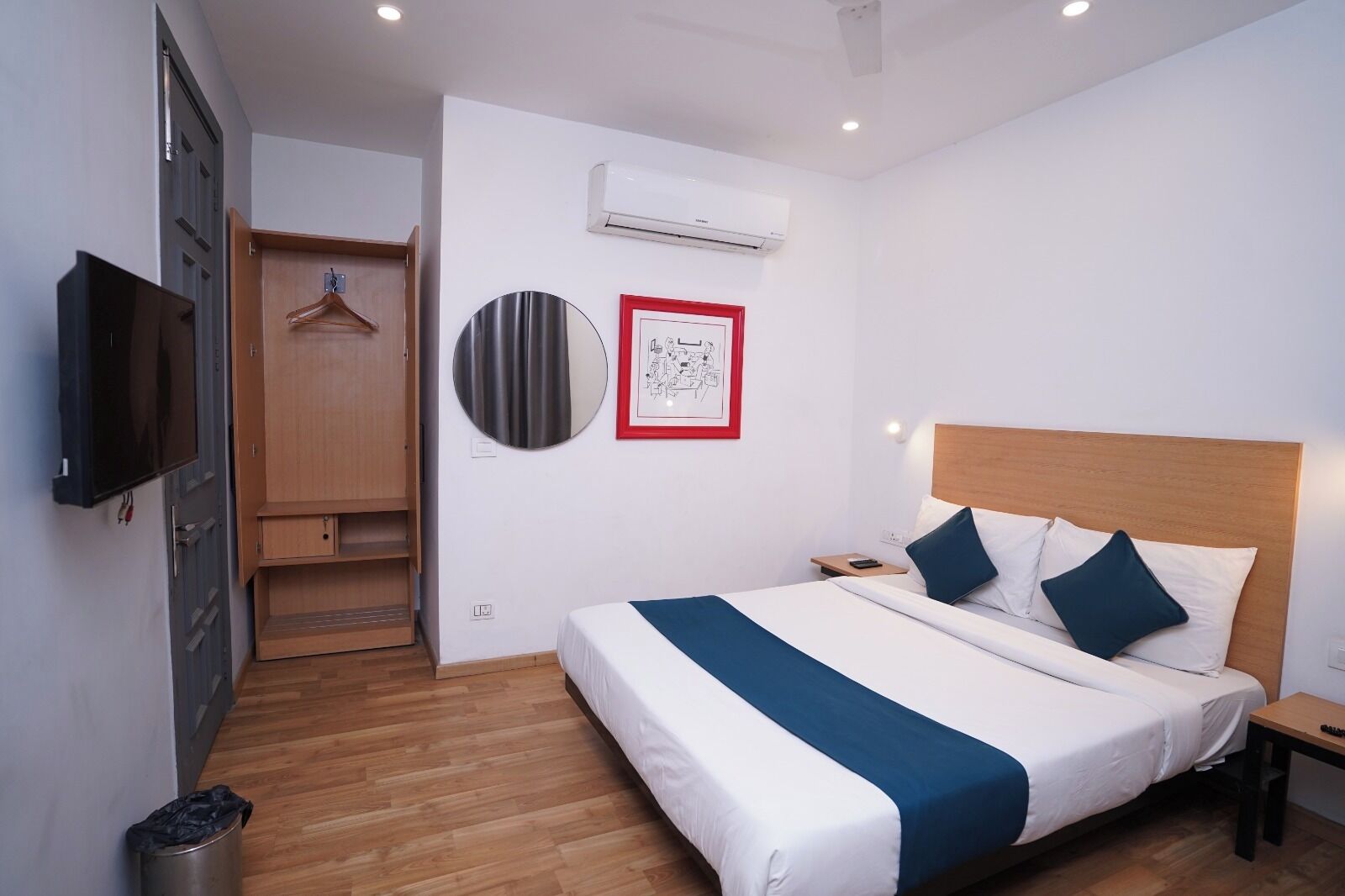 Habitación de hotel con cama, televisión, armario y unidad de aire acondicionado.