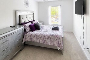 A bedroom with a bed, dresser, and a TV mounted on the wall. - Home Gym & Pool Access! North Raleigh Retreat (Raleigh)
