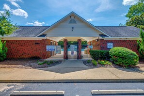 A brick building with a covered entrance and multiple signs indicating pool rules and supervision requirements. - Home Gym & Pool Access! North Raleigh Retreat (Raleigh)