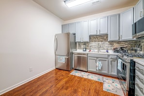 A kitchen with a stainless steel refrigerator, a dishwasher, a microwave, and a stove.