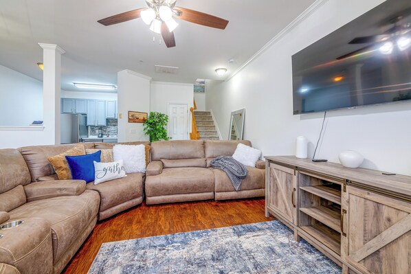 A living room with a sectional sofa, a flat-screen TV, and a wooden entertainment center. - Home Gym & Pool Access! North Raleigh Retreat (Raleigh)