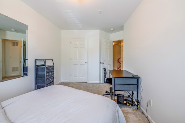 A bedroom with a bed, a desk, a chair, and a dresser.
