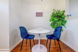 A room with a white round table, two blue chairs, a decorative plant, and a sign on the wall. - Home Gym & Pool Access! North Raleigh Retreat (Raleigh)